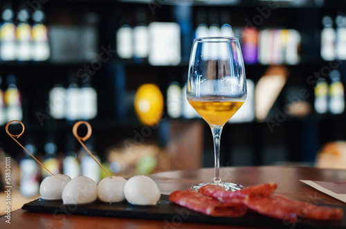 Glass of white wine and appetizer of mozzarella and ham. photo