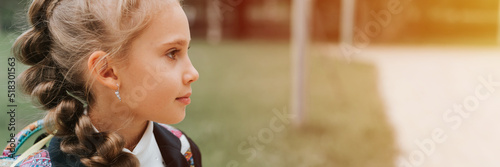 back to school. face portrait little happy kid pupil schoolgirl eight year old in fashion uniform with backpack and hairstyle braid ready going second grade first day primary school. banner. flare © Ksenia