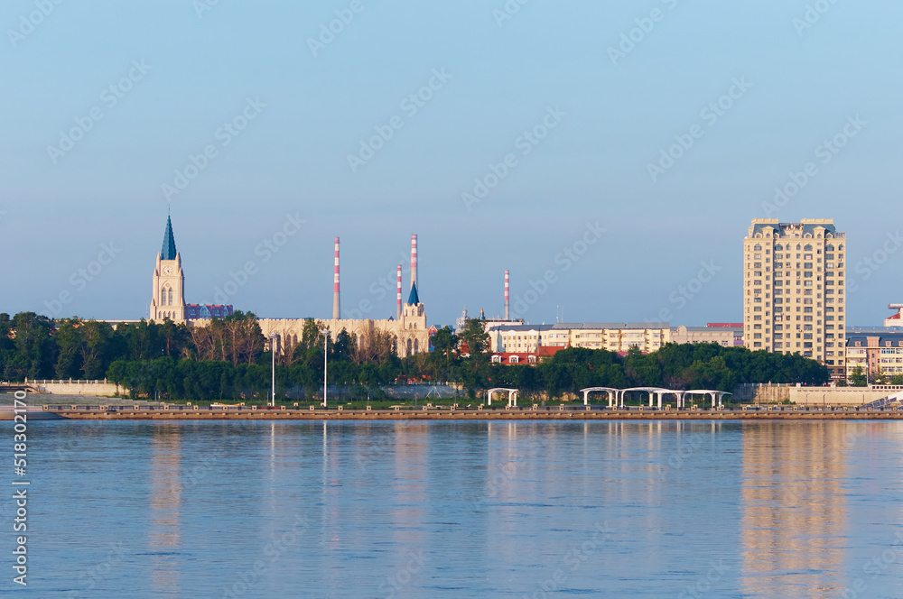 Fototapeta premium View of China from Russia across the Amur River on a summer morning. Reconstruction of the embankment of the city of Heihe.