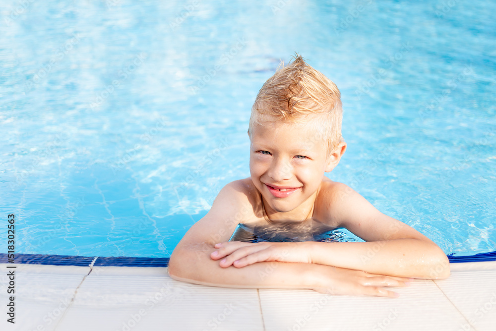 happy baby boy in the pool with blue water bathing and smiling, the concept of summer vacation and travel