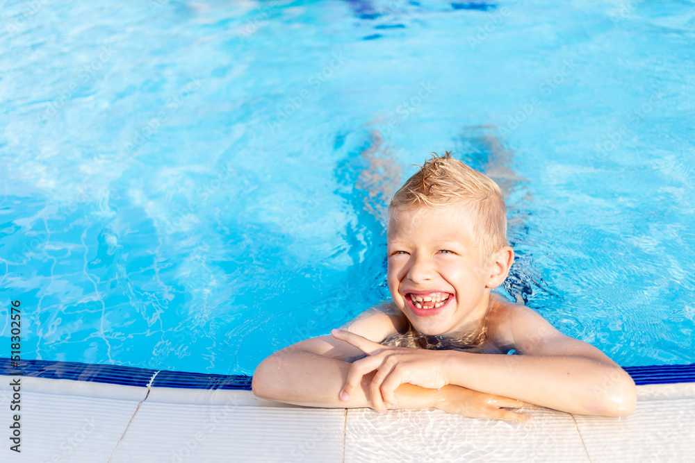 happy baby boy in the pool with blue water bathing and smiling, the concept of summer vacation and travel