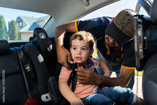 father buckling child into car seat restraint photo