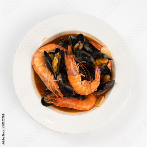 Schezwan Prawns in black bowl at dark slate background. Schezwan Prawns is indo-chinese cuisine curry dish with prawns or shrimps roasted in Schezwan Sauce.