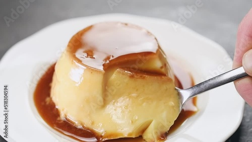 A spoon breaks a piece of classic creme caramel.
