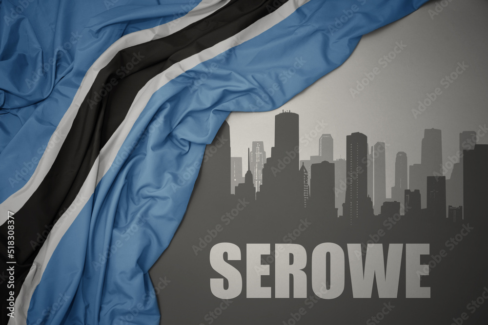 abstract silhouette of the city with text Serowe near waving colorful national flag of botswana on a gray background.