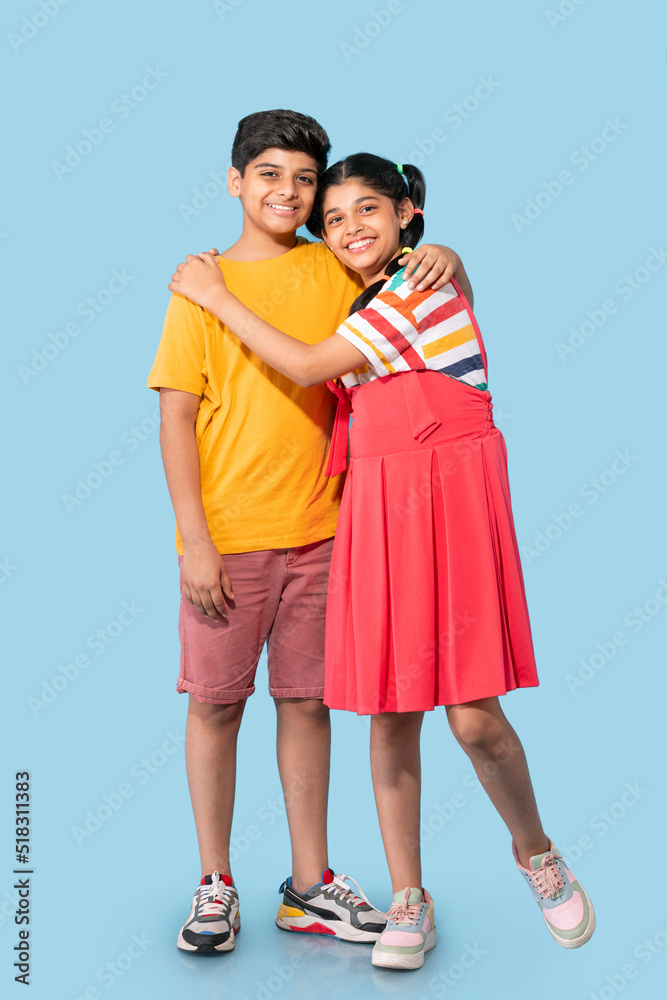 Portrait of brother and sister embracing against blue background Portrait of brother and sister embracing against blue background