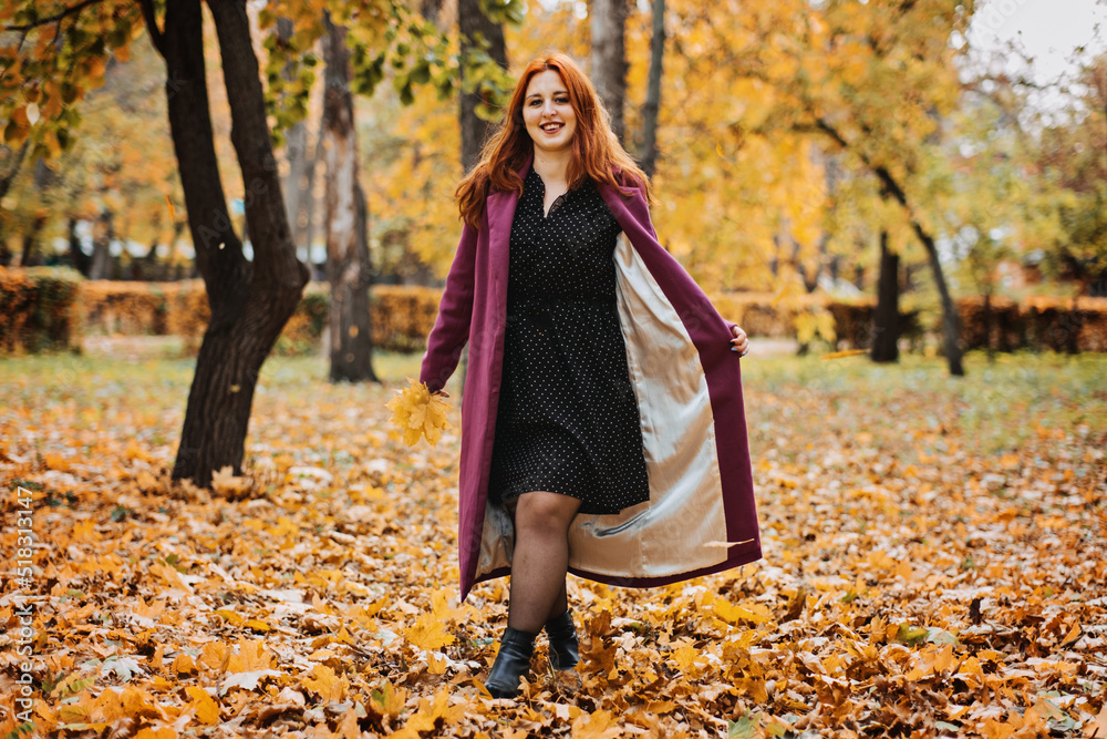 Outdoor autumn portrait of happy smiling plus size red hair woman