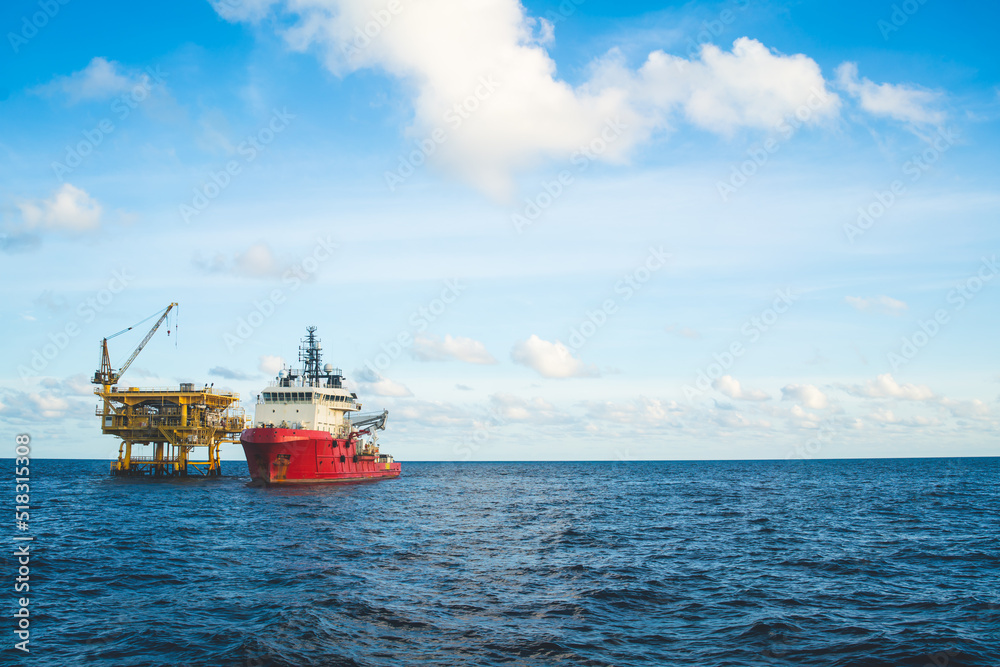 A tugboat anchors near an oil rig at an oil well to transport necessary rigging.