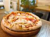 Pizza with chicken, tomatoes, corn and mozzarella is on the table in a plate. Restaurant food. selective focus