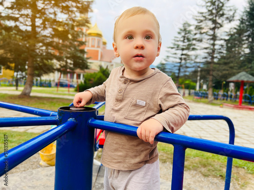 A cute boy of one and a half years rides on a swing in the playground. Children's entertainment. Selective focus © Andrii Yalanskyi
