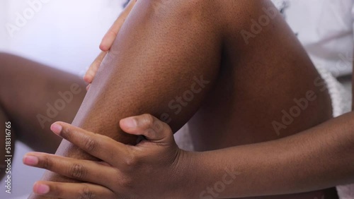 focus on hands of young woman who takes care of herself by moisturizing her legs after shower