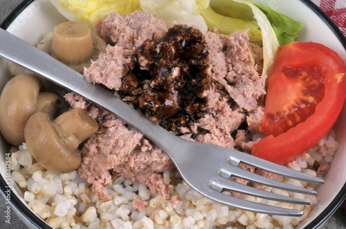 Salade de riz avec du thon, des tomates, des champignons et des olives noires servie dans une assiette en gros plan photo