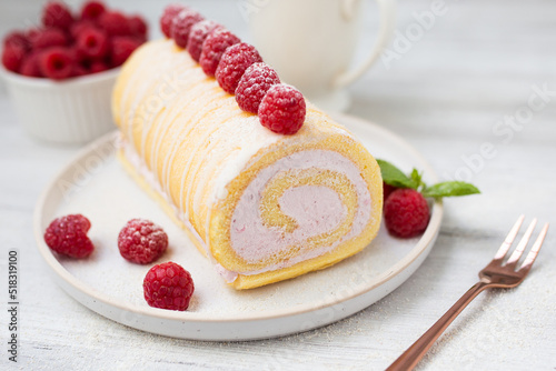Fotografi Tasty roll cake, sponge roll, Swiss roll  stuffed with cream cheese ,decorated with fresh raspberries