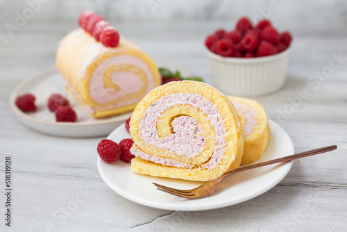Fotografi Tasty roll cake, sponge roll, Swiss roll  stuffed with cream cheese ,decorated with fresh raspberries