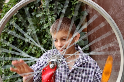 a boy is enthusiastically repairing a bicycle and watching the wheel turn