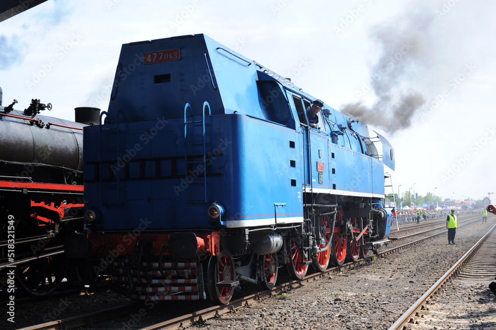 Fototapeta premium Retro historical antique steam locomotive running on rail tracks and puffing with smoke and steam in Wolsztyn, Poland, Europe