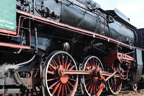 Retro historical antique steam locomotive running on rail tracks and puffing with smoke and steam in Wolsztyn, Poland, Europe