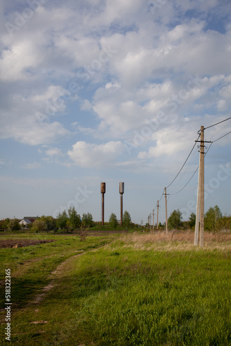 Rural landscape, houses, road. Summer in the village. Summer in Pereyaslav-Khmelnitsky, Ukraine. In the background, water towers, field, power lines. photo