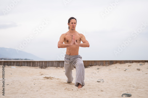 Caucasian man with long hair practicing qigong outdoors. 