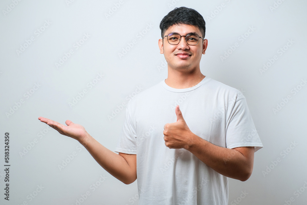 Young handsome asian man wearing casual shirt with a big smile on face, pointing with hand finger to the side looking at the camera. Young handsome asian man wearing casual shirt with a big smile on face, pointing with hand finger to the side looking at the camera.