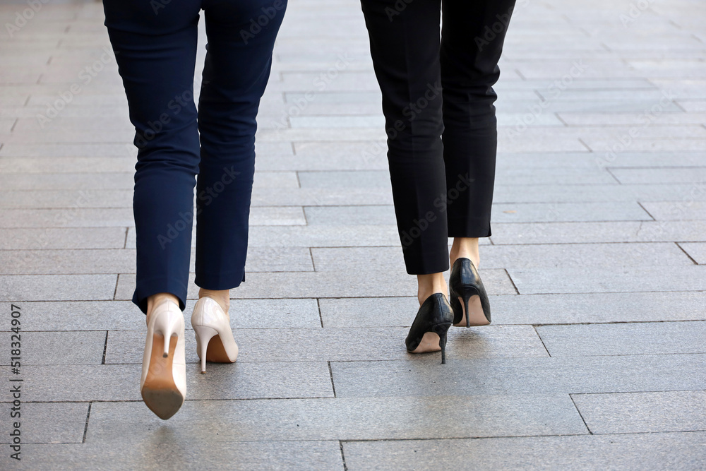 Stiletto heels, female legs in pants and high-heeled shoes. Two slim women walking on a street, fashion in summer city Stiletto heels, female legs in pants and high-heeled shoes. Two slim women walking on a street, fashion in summer city