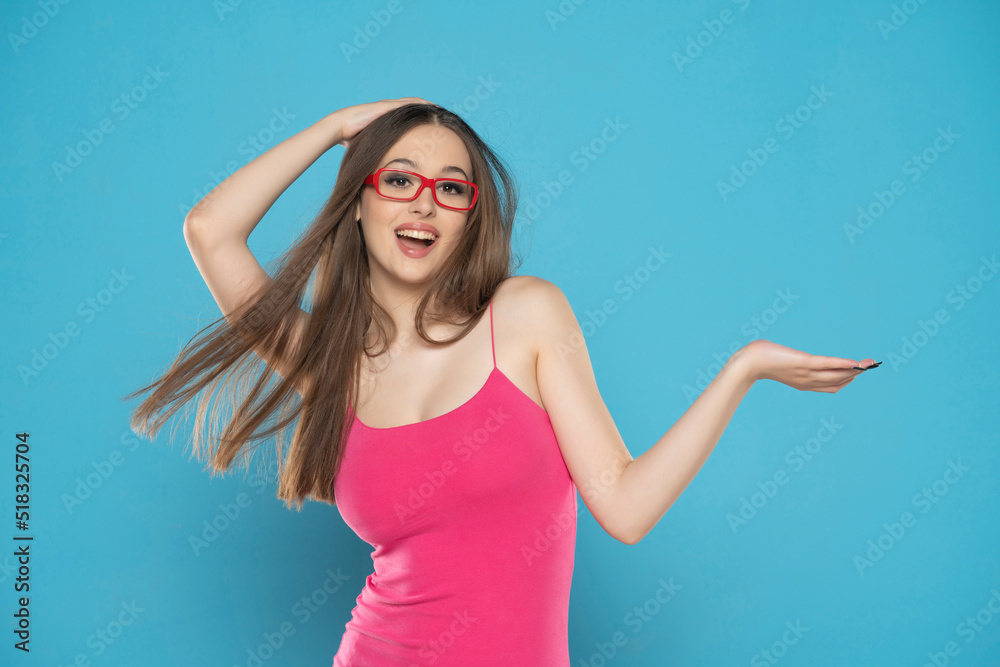 Fototapeta premium portrait of a young excited woman on a blue background, advertise some product
