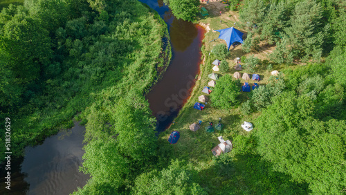 Aerial view of camping with kayaks on the beach of river on a sunny day. Modern kayaks with paddles on beach near river. © kalyanby