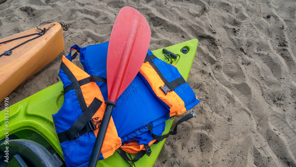 Camping with kayaks on the beach of river on a sunny day. Modern kayaks with paddles on beach near river. Camping with kayaks on the beach of river on a sunny day. Modern kayaks with paddles on beach near river.