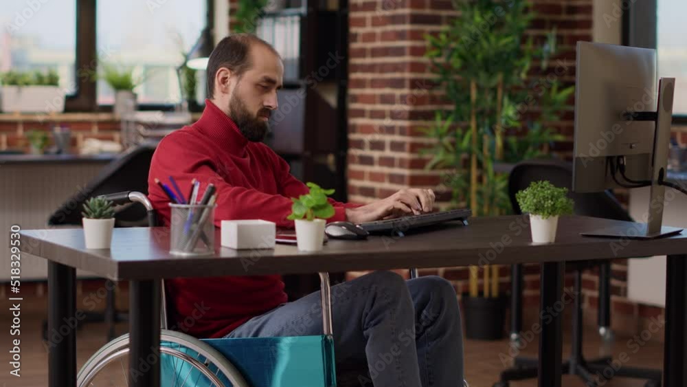 Manager with impairment working on business growth with computer at desk, witting in wheelchair. Male worker planning financial strategy to create executive company development. Manager with impairment working on business growth with computer at desk, witting in wheelchair. Male worker planning financial strategy to create executive company development.