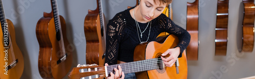 Young woman playing acoustic guitar in music shop, banner.