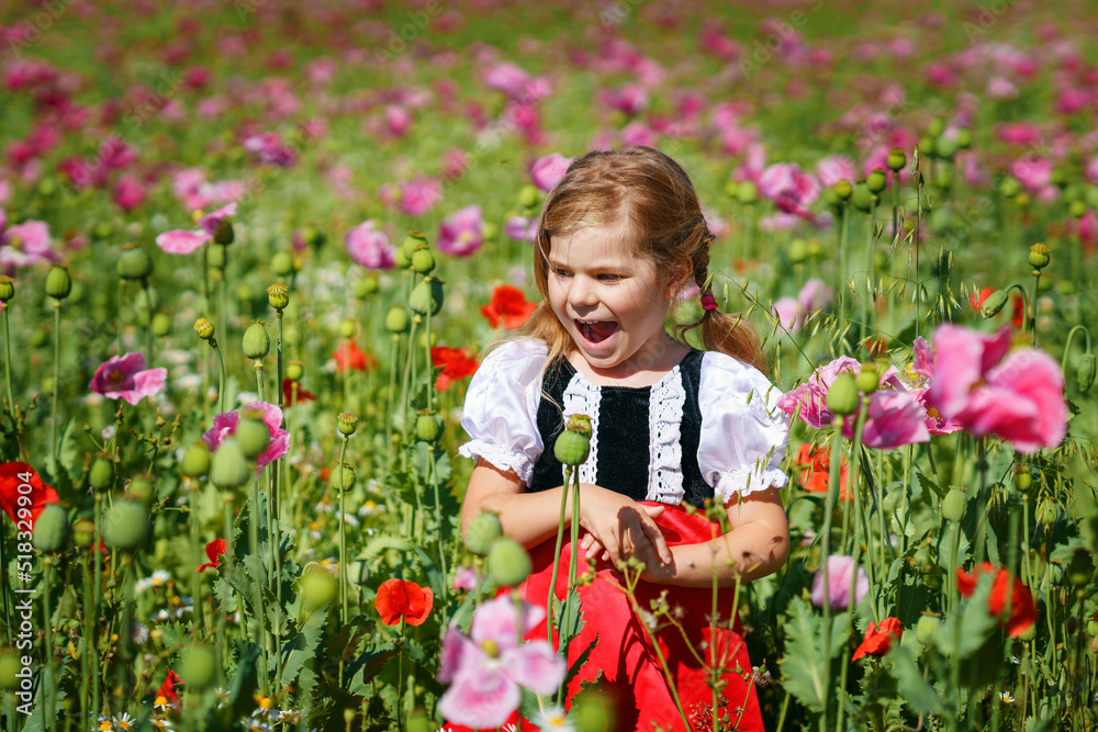 Little preschool girl in poppy field. Cute happy child in red riding hood dress play outdoor on blossom flowering meadow with pink poppies. Leisure activity in nature with children. Little preschool girl in poppy field. Cute happy child in red riding hood dress play outdoor on blossom flowering meadow with pink poppies. Leisure activity in nature with children.