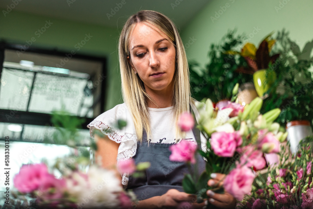 Beautiful girl florist working in flower shop. Making decorations and arrangements. Flowers delivery, creating order. Small business. .