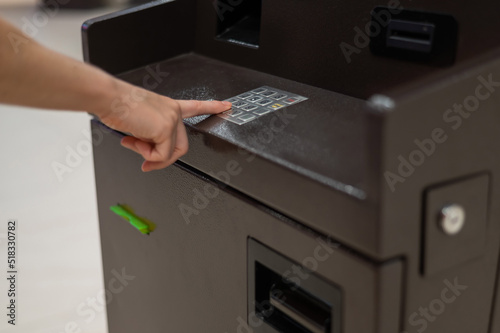 Faceless woman dialing bank card pin at ATM.  photo