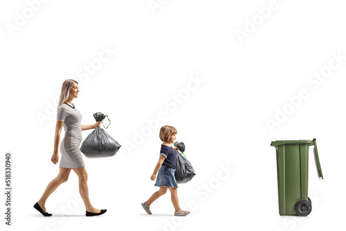 Mother and daughter with plastic bags walking towards a trush bin photo
