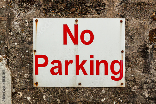 Sign warning NO PARKING on an old stone wall in a public place. Information for drivers on the city street wall. © Andrii A