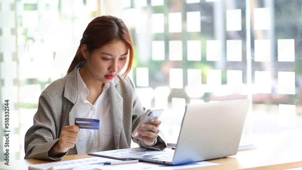 Asian woman holding credit card using mobile phone and entering payment code for online shopping. Asian woman holding credit card using mobile phone and entering payment code for online shopping.