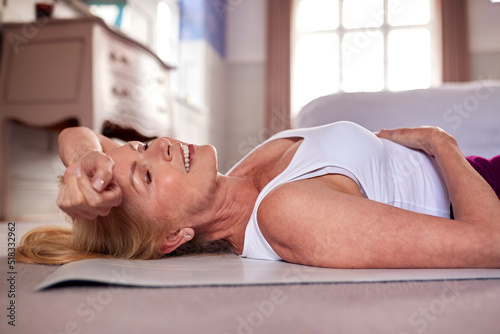 Active Mature Woman Exercising Doing Yoga On Mat At Home