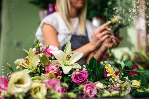 Beautiful girl florist working in flower shop. Making decorations and arrangements. Flowers delivery  creating order. Small business. .