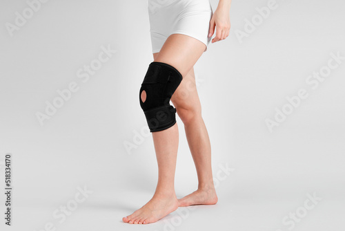 Knee Support Brace on leg isolated on white background. Elastic orthopedic orthosis. Anatomic braces for knee fixation, injuries and pain. Protective knee joint bandage sleeve. Trauma, rehabilitation