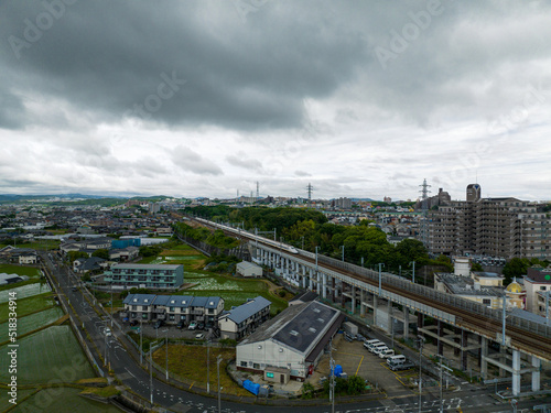 Shinkansen on elevated tracks through residential area under storm clouds