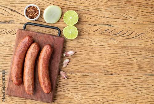 Calabrese pork sausage over wooden board with seasonings and copy space photo