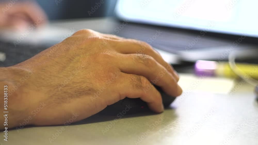 A man's hand holds a computer mouse. Laptop on the table. Receiving the information. Photo and video content.. Surfing on the Internet. Tester. User. IT-specialist. Close-up.