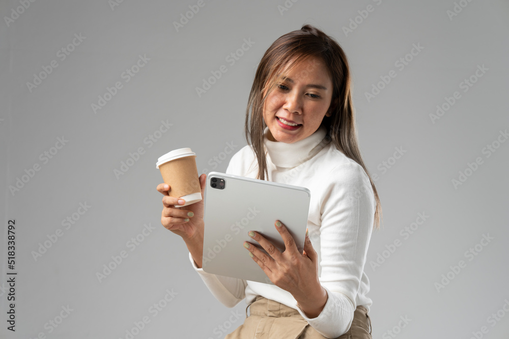 Asian woman in white shirt holding tablet and coffee cup in studio against white background. Asian woman in white shirt holding tablet and coffee cup in studio against white background.