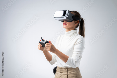 Asian women with using virtual reality headset or VR glass with joystick isolate on gray background