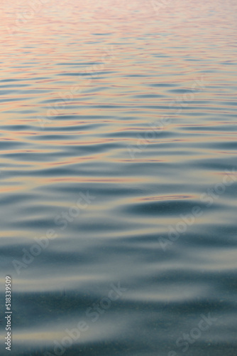Calm sea waves with sunset reflection