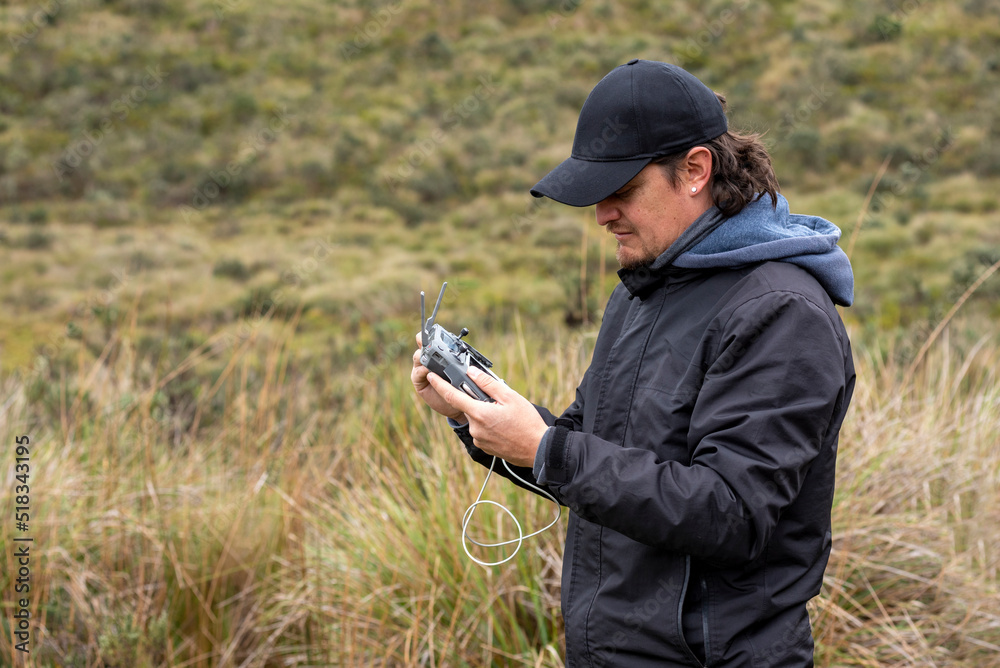 young man flying and operating a drone in the middle of a field young man flying and operating a drone in the middle of a field