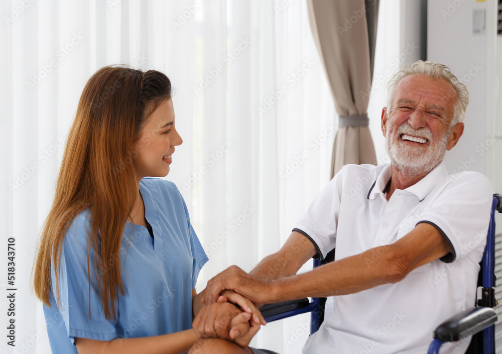 Fototapeta premium female doctor helping care holding hands to encourage talk Caucasian older man, older adult, patient in a wheelchair