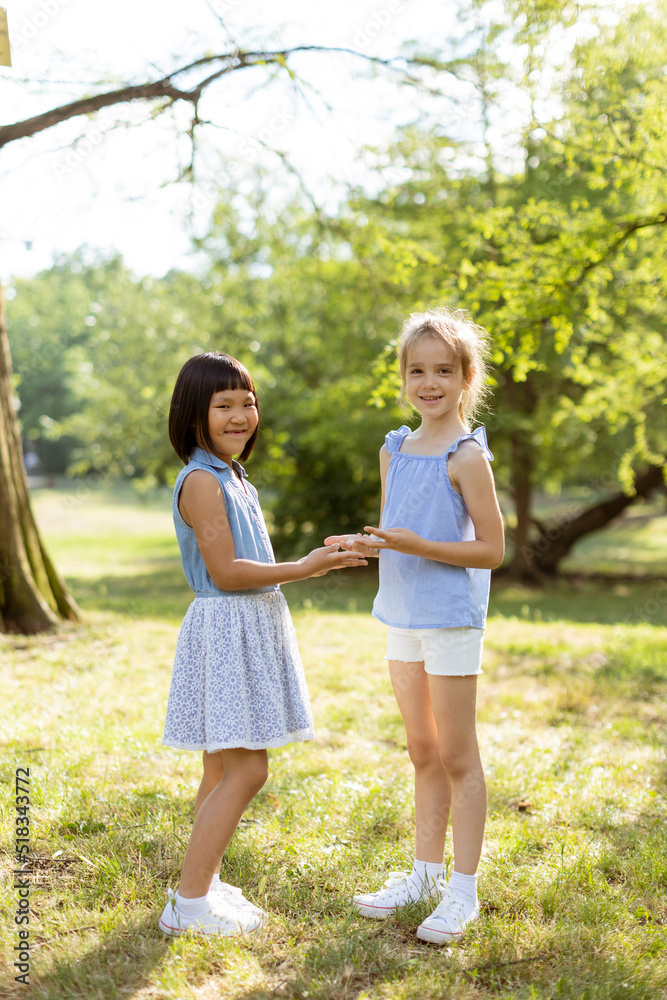 Fototapeta premium Cute asian and caucasian girl having fun in the park