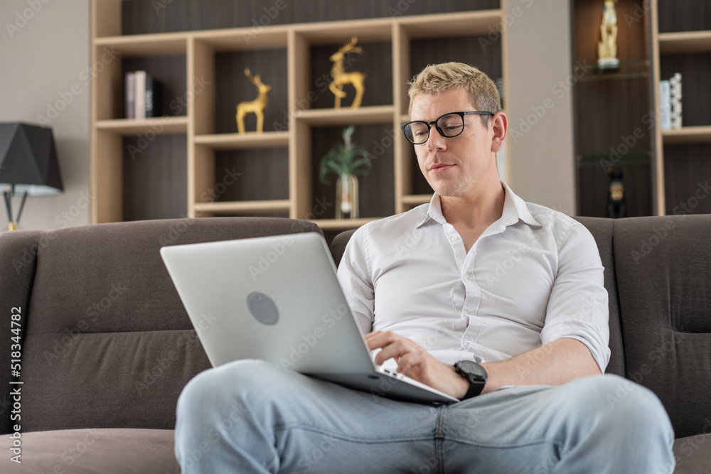 Caucasian business man working with laptop or watching movie on couch in the living room at home. shopping online, browsing and learning on the internet. hobby and activity on weekend Caucasian business man working with laptop or watching movie on couch in the living room at home. shopping online, browsing and learning on the internet. hobby and activity on weekend