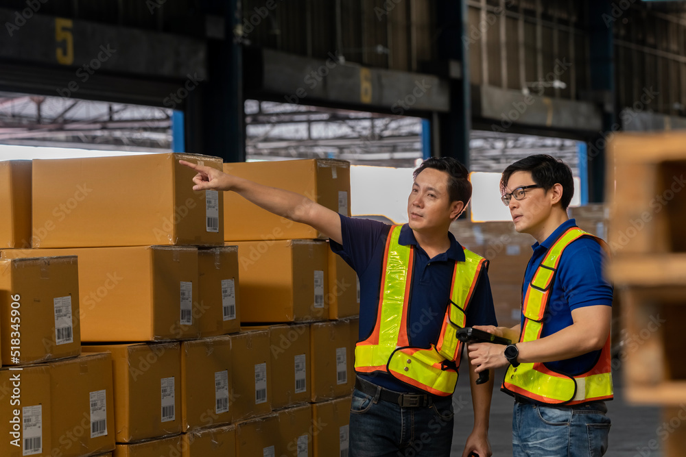 A man in charge of a large warehouse is checking the number of items in the warehouse that he is responsible for. checking goods in a warehouse by scanning a barcode. A man in charge of a large warehouse is checking the number of items in the warehouse that he is responsible for. checking goods in a warehouse by scanning a barcode.